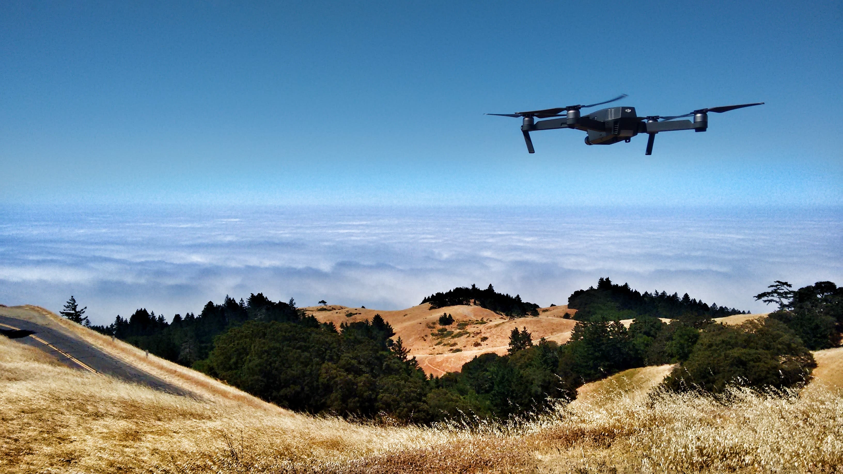 black drone on air over cloudy sky at daytime